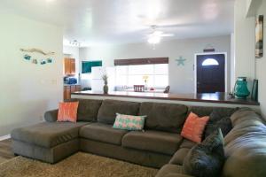 a living room with a brown couch with pillows at North Shore Bungalow in Mokuleia