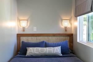 a bedroom with a bed with two lights on the wall at North Shore Palms in Mokuleia