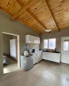 a kitchen with white cabinets and a wooden ceiling at Ancar Añelo in Añelo