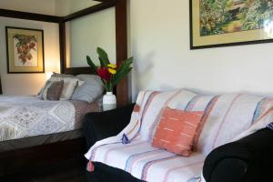 a bedroom with a bed and a couch with a blanket at North Shore Studio in Mokuleia