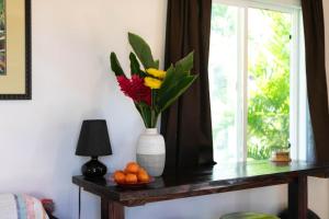 a vase with flowers on a table next to a window at North Shore Studio in Mokuleia