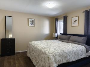 a bedroom with a bed and a dresser and a mirror at Spacious 4BR with King Suite - Garage - Netflix in Lloydminster