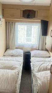 a small room with three beds and a window at 10 Berth Caravan - Meadow View in Skegness +13 photos