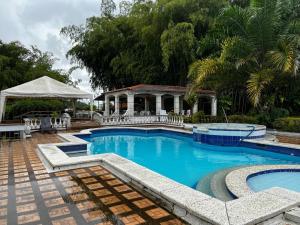 a swimming pool with a gazebo in the background at mansion cafetera in Quimbaya