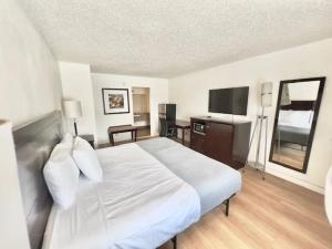 a bedroom with a large bed and a flat screen tv at Airport Inn in Tulsa