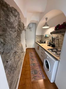 a kitchen with a washer and a stone wall at Maison Raphael Positano in Positano