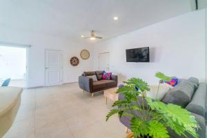 a living room with a couch and a chair at Walk to 5th Ave & Beach - Pools, Balcony & Parking in Playa del Carmen