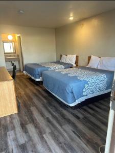 two beds in a hotel room with wood floors at Best Economy Inn & Suites in Bakersfield