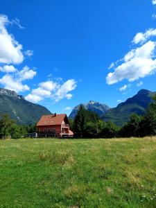 a house in a field with mountains in the background at Počitniška hiša Nad Sočo in Bovec