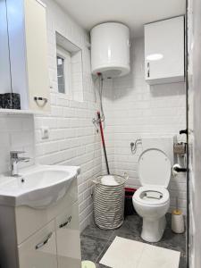 a white bathroom with a toilet and a sink at Lane Stay Studio in Beograd