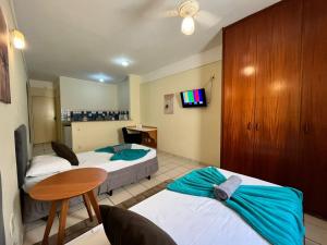 a hotel room with two beds and a table at GoHost Suítes - 2 Ruas do Shopping Santa Úrsula in Ribeirão Preto