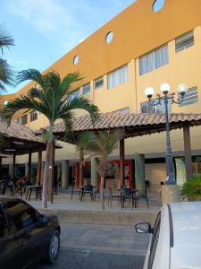 a building with tables and palm trees in front of it at FLAT 231 Shopping Amarração in Luis Correia