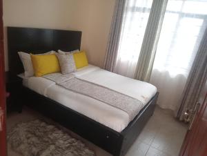 a bed with yellow and white pillows in a bedroom at Shanvinhomes -1 bedroom Apartment in Skuta-Nyeri Town in Nyeri