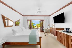 a bedroom with a white bed and a television at Couples Swept Away in Negril