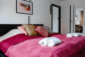a pink bed with towels on top of it at Apartament Patka Wysoki STANDARD in Grudziądz