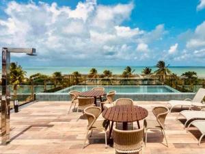 a patio with tables and chairs and a view of the ocean at Cabo Branco - Fortune in Tambaú