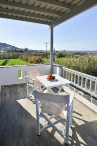 a white table and chairs on a balcony with the ocean at Agros Estate in Plaka