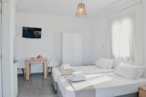 a white room with two beds and a table at Agros Estate in Plaka
