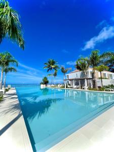 a swimming pool in front of a house with palm trees at White Sand Villa - infinity pool in Paea