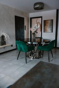 a dining room with a table and green chairs at Apartament Patka Wysoki STANDARD in Grudziądz +20 photos