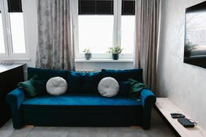 a blue couch in a living room with windows at Apartament Patka Wysoki STANDARD in Grudziądz