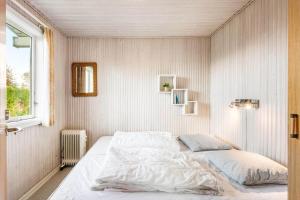 a bedroom with a bed with white sheets and a window at LL261-Humble-Gyvelvaenget-1 in Spodsbjerg