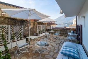a patio with chairs and tables and an umbrella at Loving Loppia - Glicine in Bellagio