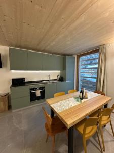 a kitchen with a wooden table and yellow chairs at Maison ValGià in Champoluc