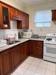 a kitchen with wooden cabinets and a white stove top oven at Patch&Porch Cottage in Port Antonio
