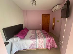 a bedroom with a bed with a pink and white comforter at Encantador, tranquilo y centrico in Málaga