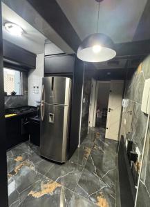 a kitchen with a stainless steel refrigerator in it at AP FRENTE MAR Compacto, Completo e Confortável in São Vicente