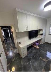 an empty room with a desk and a tv at AP FRENTE MAR Compacto, Completo e Confortável in São Vicente