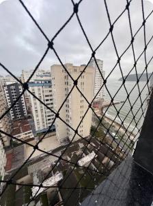 a view of a city from a wire fence at AP FRENTE MAR Compacto, Completo e Confortável in São Vicente