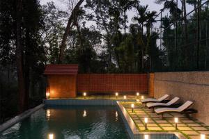 a swimming pool with loungers and lights in a backyard at 1st Miracle By Mirth, Mythadi , Coorg in Ammatti