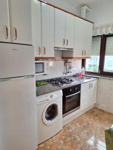 a kitchen with white cabinets and a washer at El Burby II in Somo