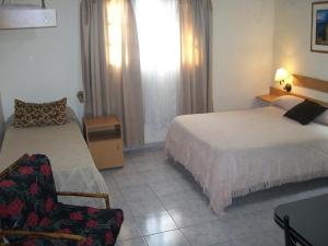 a hotel room with two beds and a chair at Complejo turistico ALOJARTUR in San Rafael