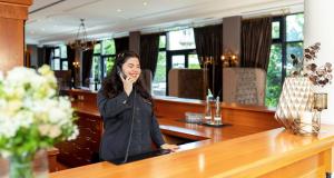 a woman standing at a bar talking on a cell phone at Victor's Residenz-Hotel Berlin Mitte in Berlin +30 photos