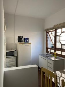 a small kitchen with a refrigerator and a table at Apartamento central próximo à catedral com 2 quartos e 2 banheiros in Santo Ângelo