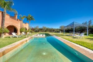a swimming pool in the middle of a yard with palm trees at Villa Maloulou in Marrakesh