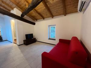 a living room with a red couch and a tv at La Dimora Della Volpe in Calice Ligure