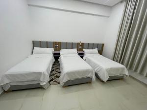 three beds in a room with white walls at Hotel kairouan in Fez