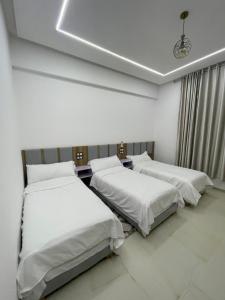 two beds in a room with white walls at Hotel kairouan in Fez