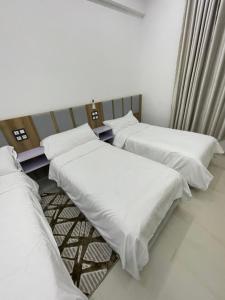 three beds in a room with white sheets at Hotel kairouan in Fez