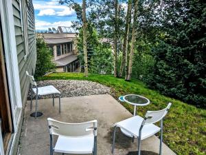 two chairs and a table on a patio with a yard at Mountain Adventure Basecamp + Hot Tubs in Winter Park