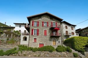 an old stone house with red shutters on a street at Belmonte Terrazzo in Pianello Del Lario