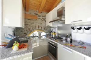 a kitchen with white cabinets and a stone wall at Belmonte Terrazzo in Pianello Del Lario +27 photos