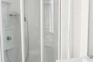 a shower with a glass door next to a toilet at Camping Village Torre Pendente in Pisa