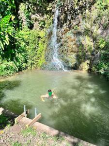a person swimming in a pond in front of a waterfall at Oasis nature et cascade privée in Atihiva