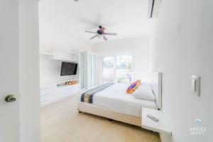 a white bedroom with a bed and a ceiling fan at Walk to 5th Ave & Beach - Pools, Balcony & Parking in Playa del Carmen