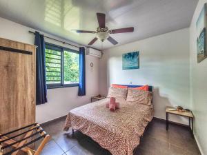 a bedroom with a bed and a ceiling fan at Teahupo'o Lodge Tahiti - Maison familiale au cœur du village - Canoës inclus in Teahupoo